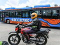 Un conducteur de moto à Nairobi, le 19 octobre 2022, à côté d'un bus électrique. 