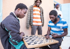 Migrants play a board game at IOM Transit Center in Agadez, Niger (2016).