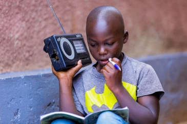 Igihozo, 11, listens to a lesson on a radio after his school was closed in Rwanda.