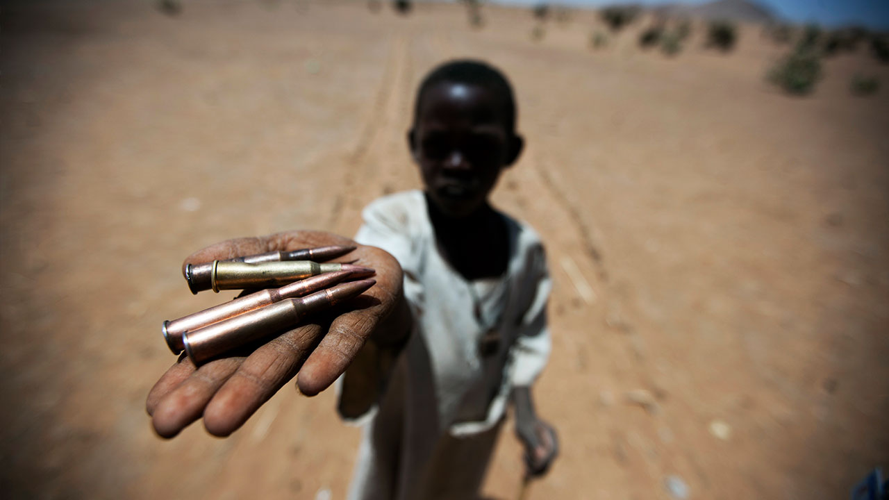 Un jeune garçcon tend la main, remplie de munitions.