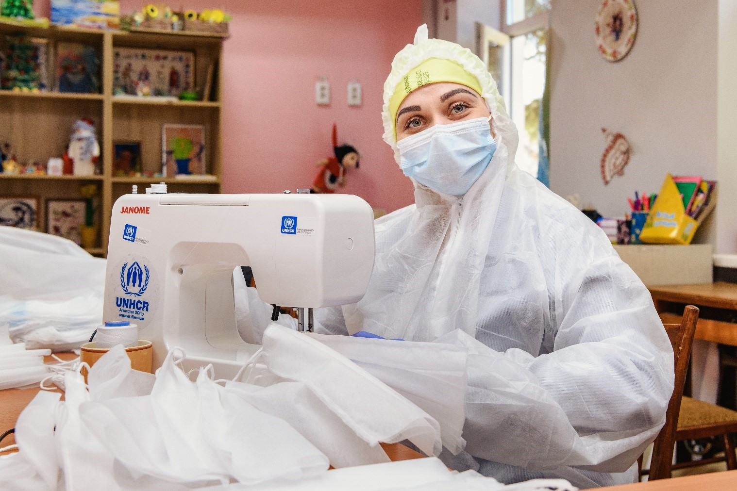 Una mujer con equipo de prptección fabrica mascarillas contra el COVID-19 con su máquina de coser 