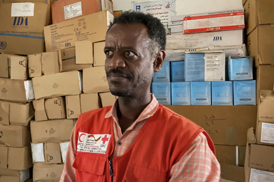 Un médico refugiado etíope con cajas de suministros en segundo plano.