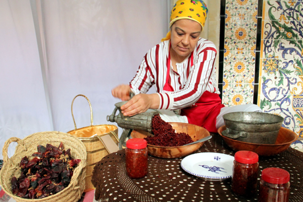 A woman grinds peppers into paste. 
