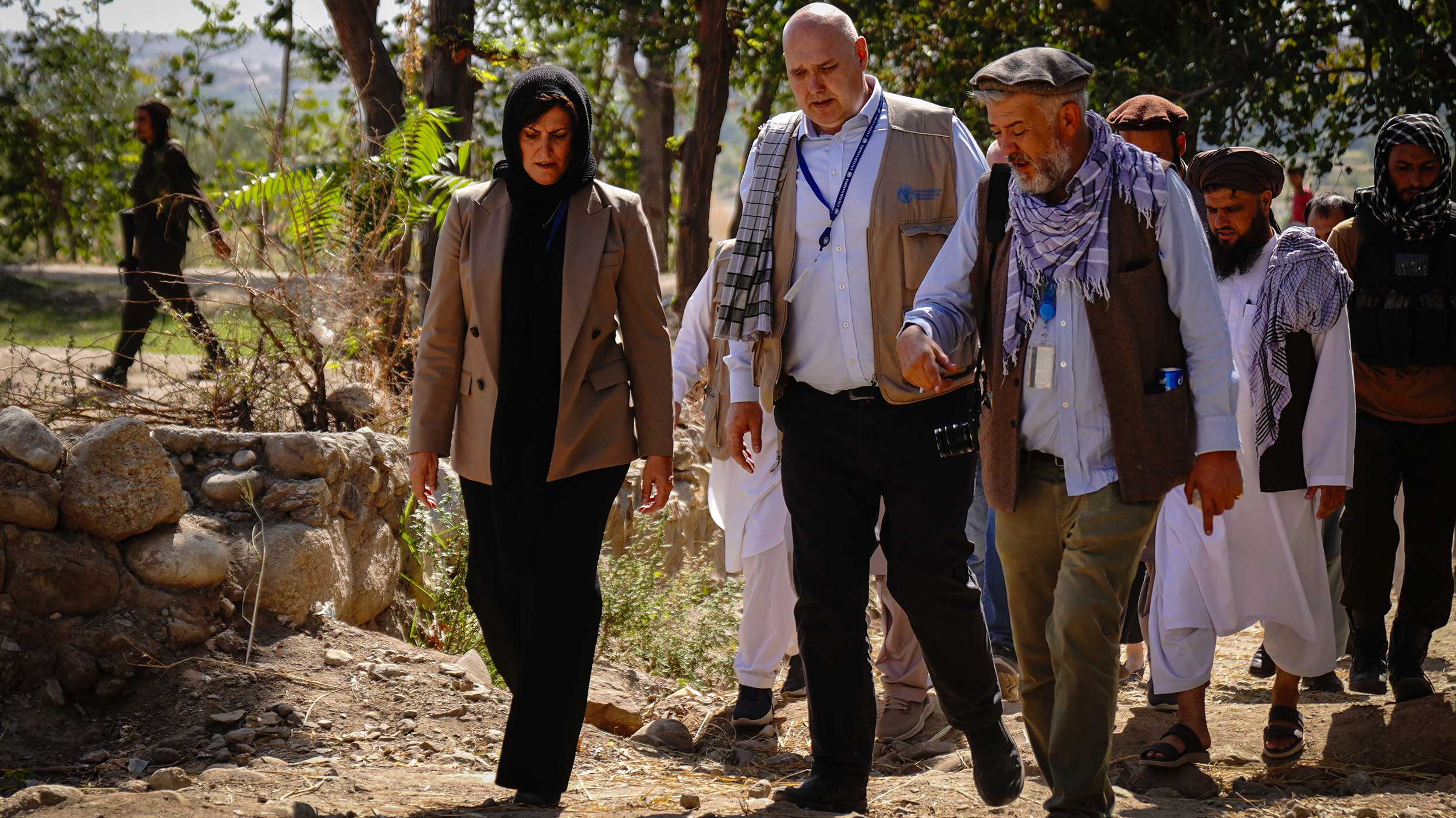 Beth walks with FAO Emergencies Director Rein Paulsen and other men, some in traditional Afghan attire.