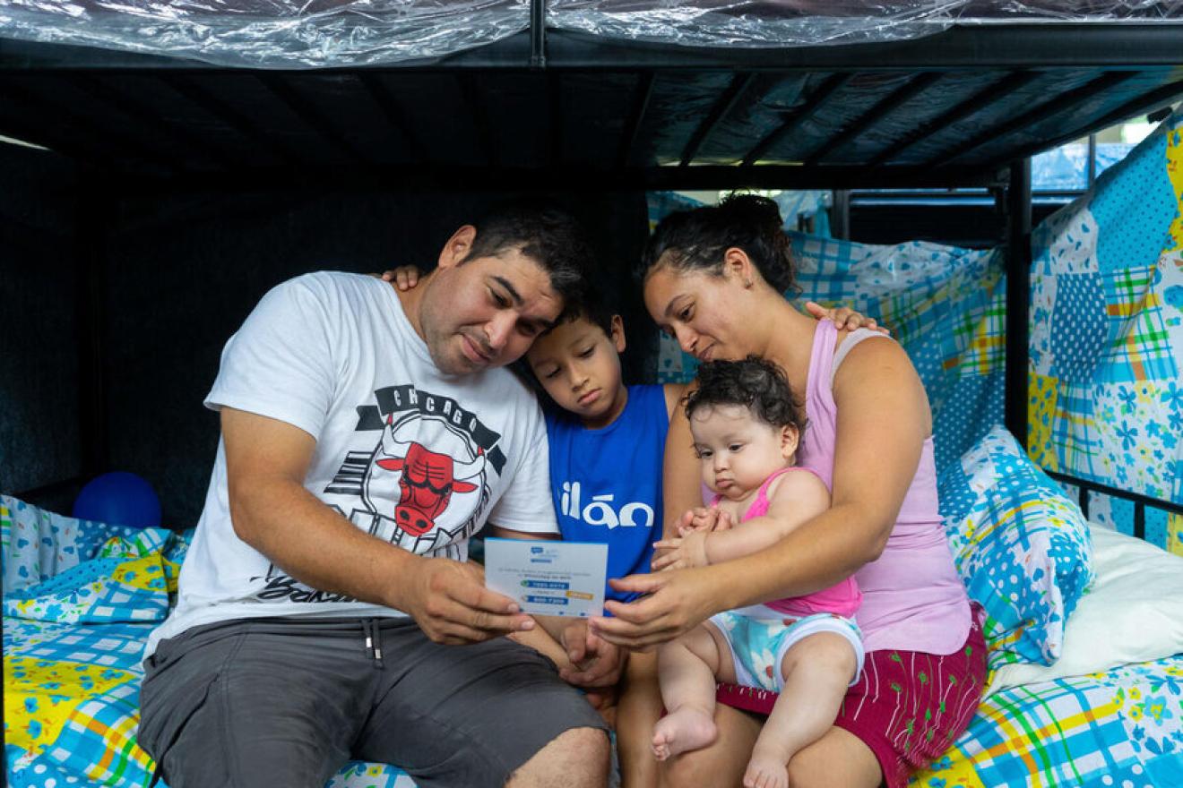 hristian Hernández, Yessenia Martínez y sus hijos observan un vale digital que les permitirá comprar víveres una vez regresen a casa.