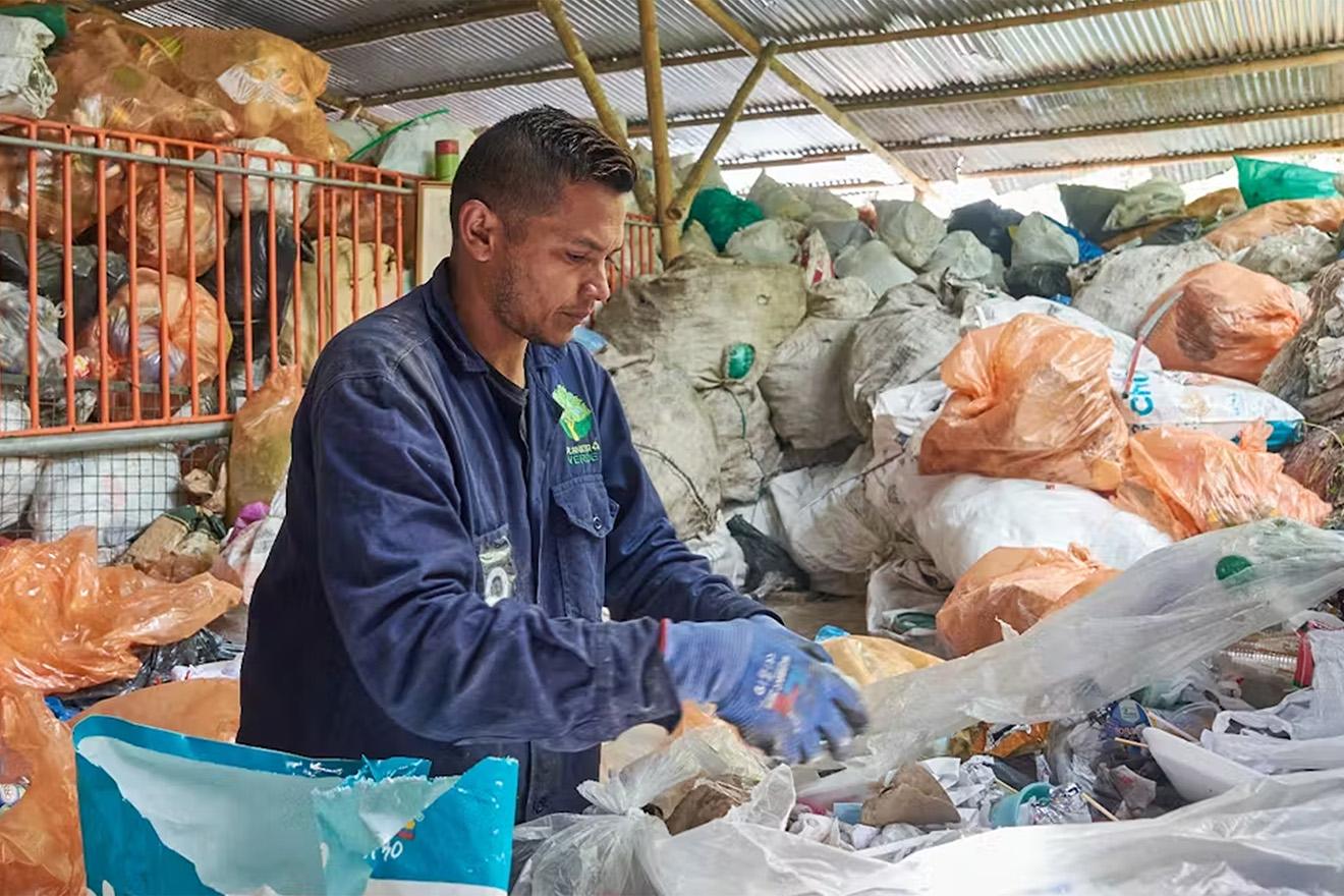 Un trabajador de reciclado clasifica los desperdicios de bolsas de basura
