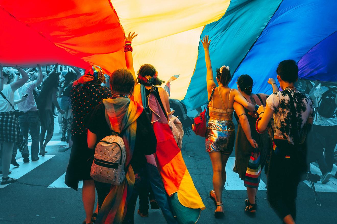 marching people hold a large rainbow flag