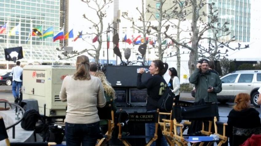 Law and Order staff are standing outside the UN headquarters building with filming equipment. 