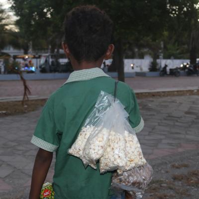 Eight-year-old Ano from Dili in Timor-Leste, spends close to nine hours daily selling popcorn and other snacks in town.  The money from these sales helps supplement the income for his family of seven. @UNICEF Timor-Leste/2024/DMonemnasi 